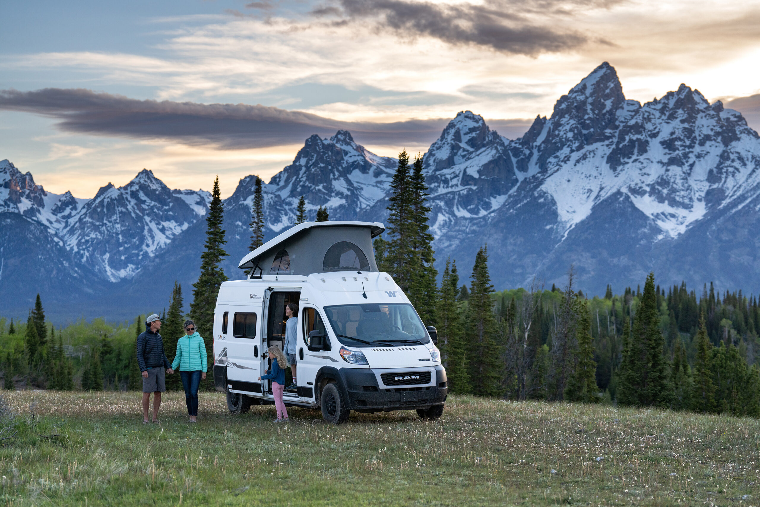 Family outside of luxury RV by stunning mountains of Grand Teton National Park